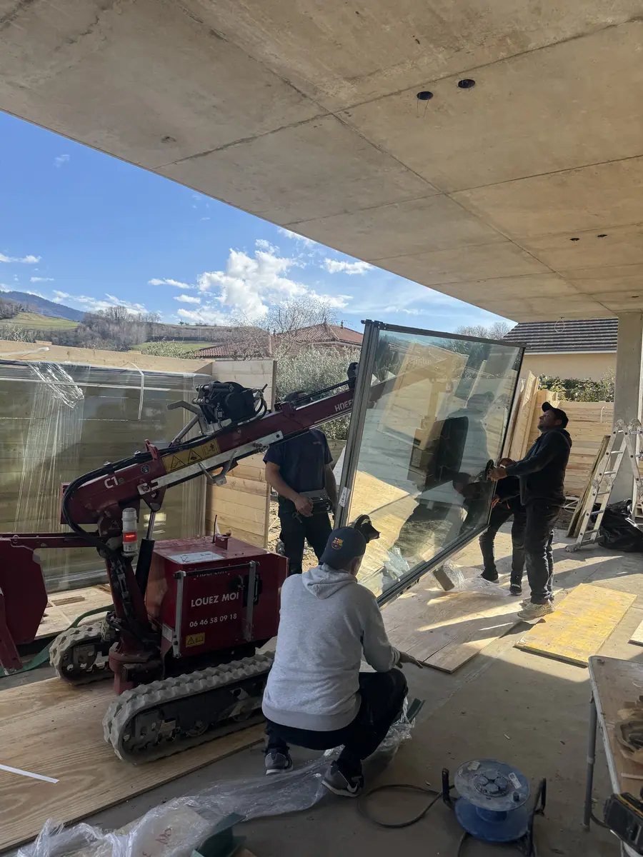 Two workers installing a large-format glazed unit with a mini crane