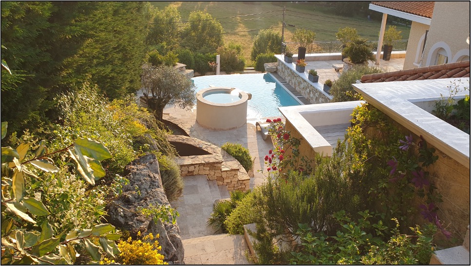 Vue plongeante sur le jardin d'une villa ensoleillée rénovée par Infinity Partners 