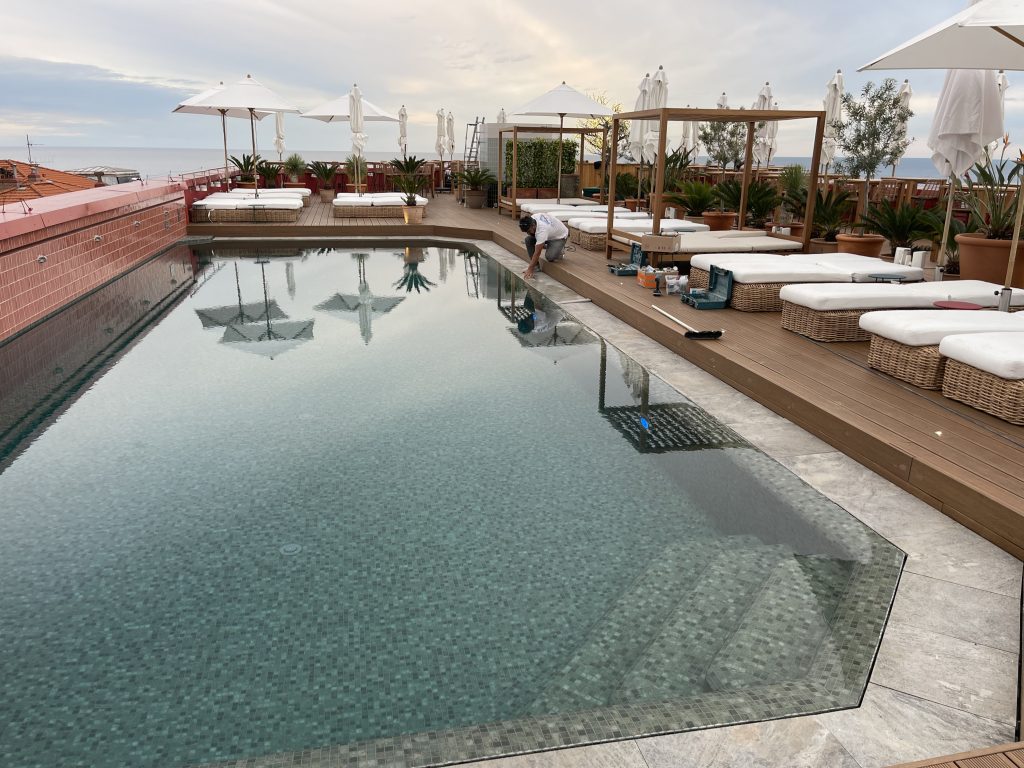 vue sur une grande piscine avec terrasse bois et espaces détente luxe en cours de rénovation avec Infinity Partners 